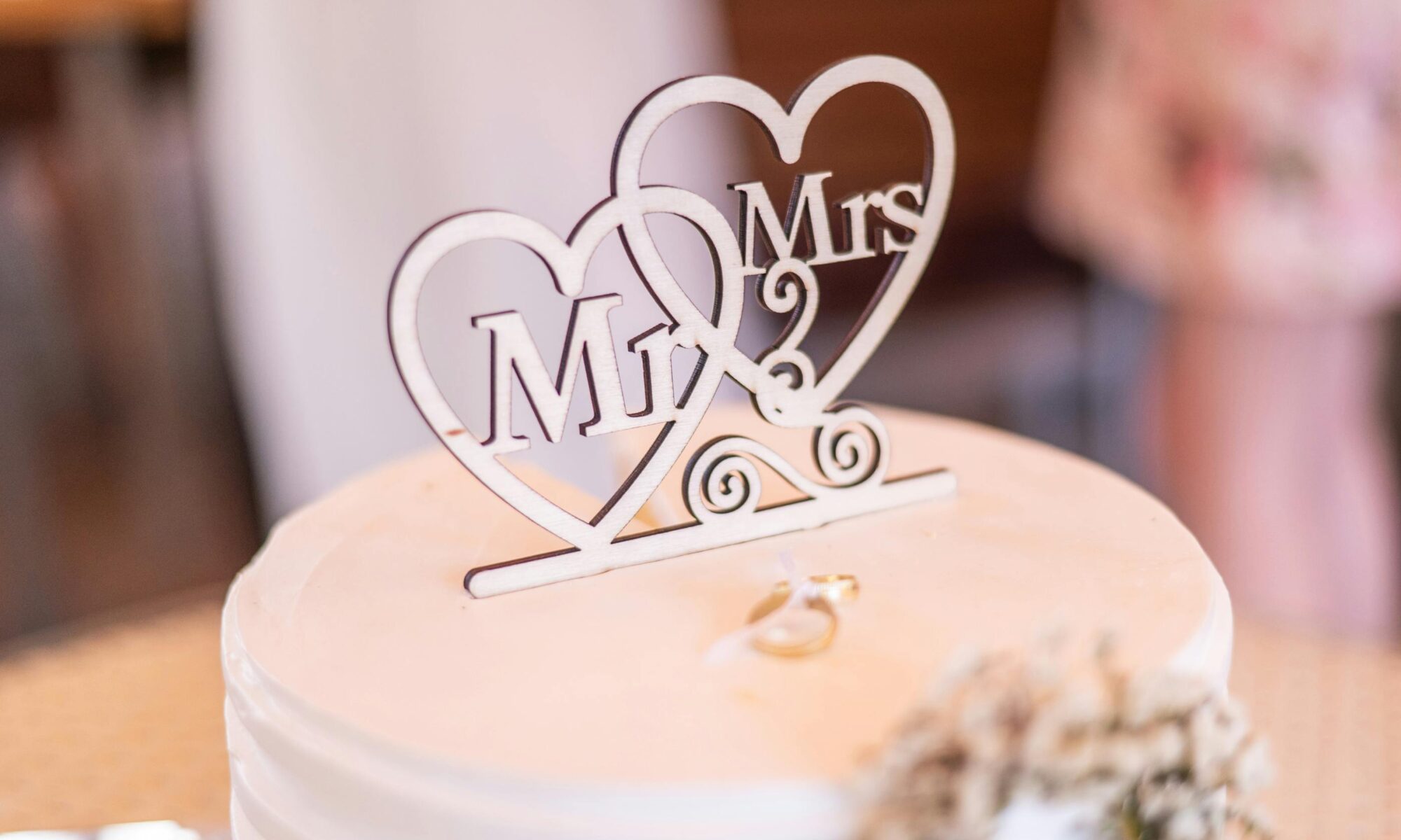 Close-up of a wedding cake with 'Mr & Mrs' topper, symbolizing romance and celebration.