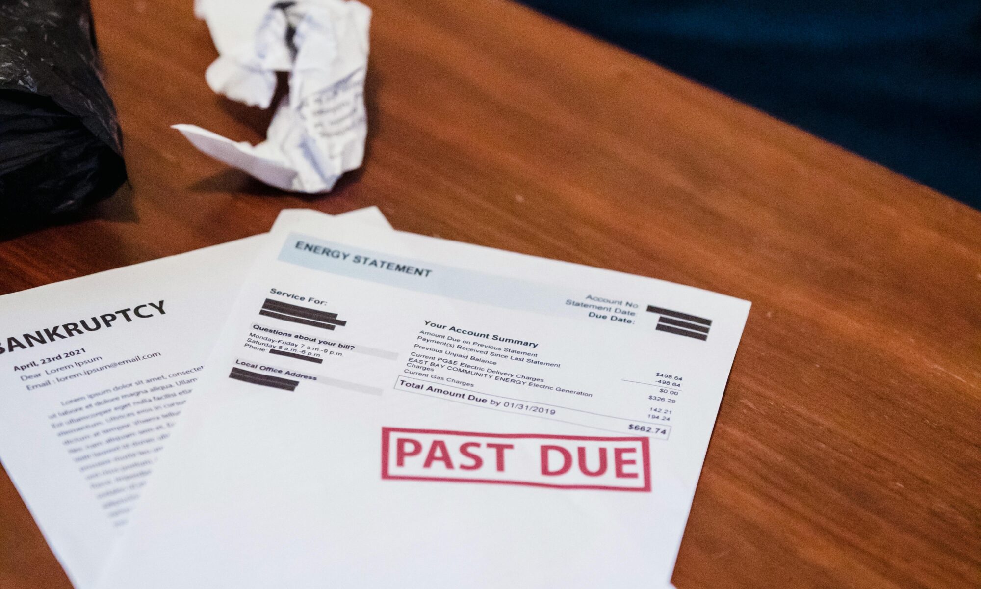 Close-up of past due financial documents on a wooden table, suggesting economic hardship.